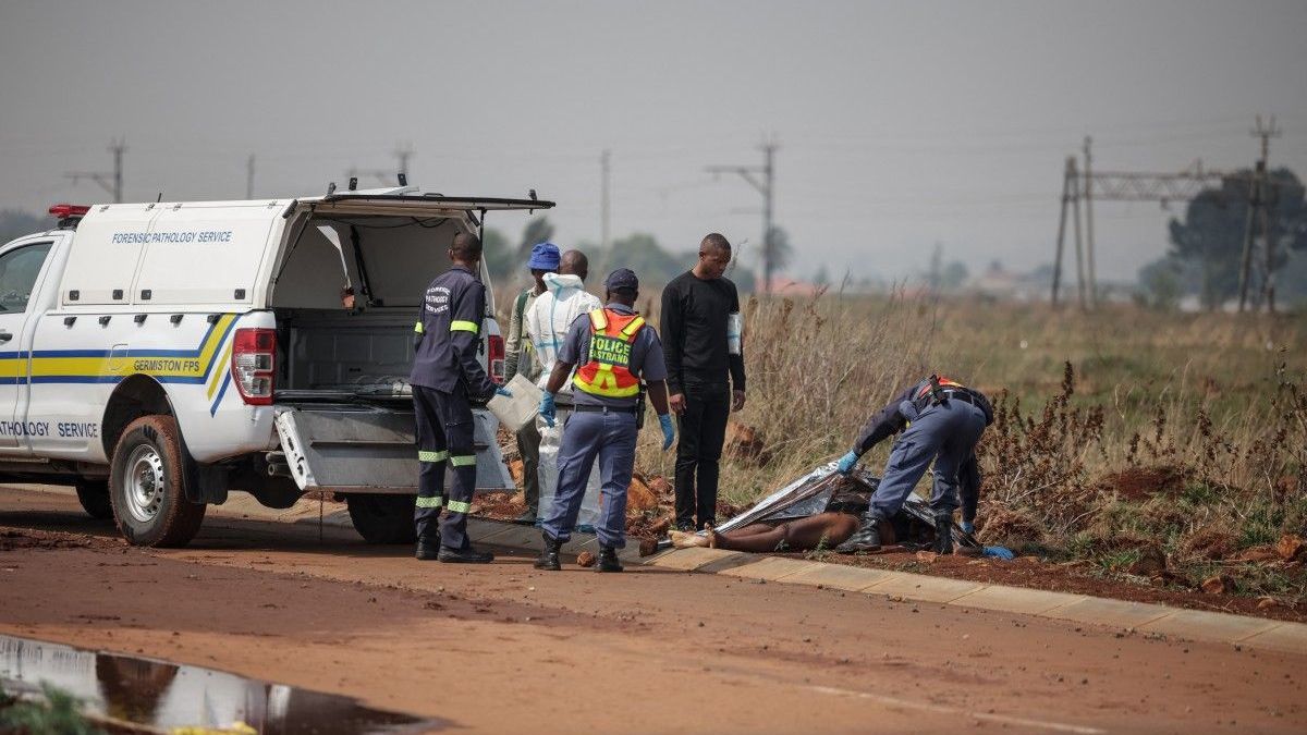Agentes del Servicio de Policía de Sudáfrica (SAPS) y servicios de patología forense trabajan en la escena del crimen donde se descubrió el cuerpo de una mujer en Boksburg